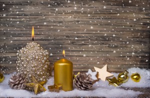 Weihnachtsdekoration mit Kerzen und Sternen vor einer Holzwand mit Kunstschnee