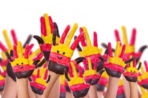 Hände die in der Luft sind mit Deutschlandfarben angemalt und Smileys auf der Handinnenfläche