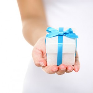 weißes Geschenk mit blauer Geschenkschleife in einer Hand