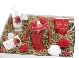 Geschenkbox mit Tasse und zwei roten Figuren in der Mitte und Rosen drumherum