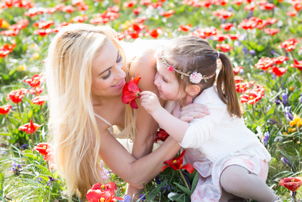 Muttertag mit Mutter und Kind auf einer grünen Wiese mit roten Blumen