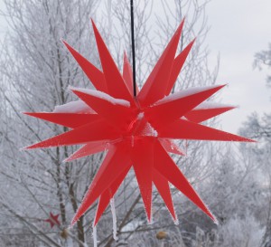 roter Adventsstern leicht bedeckt mit Schnee