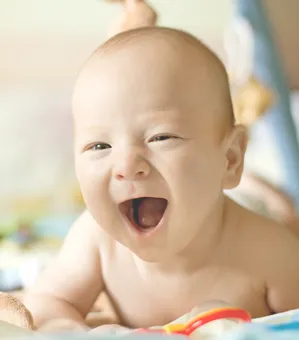 lachendes Baby liegt auf der Decke Moodbild